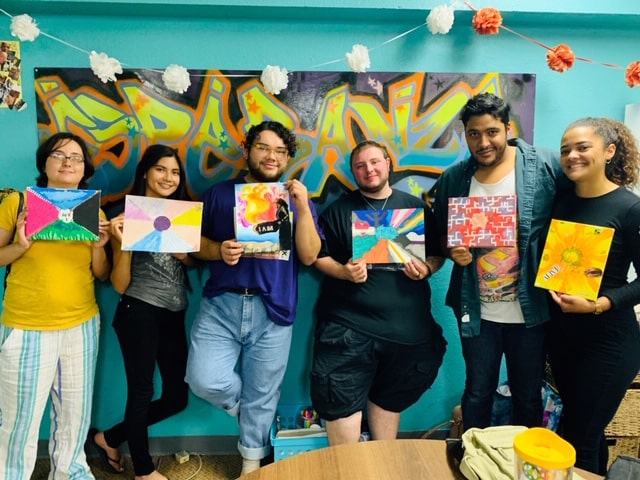 Group of artists standing together holding their finished creative projects