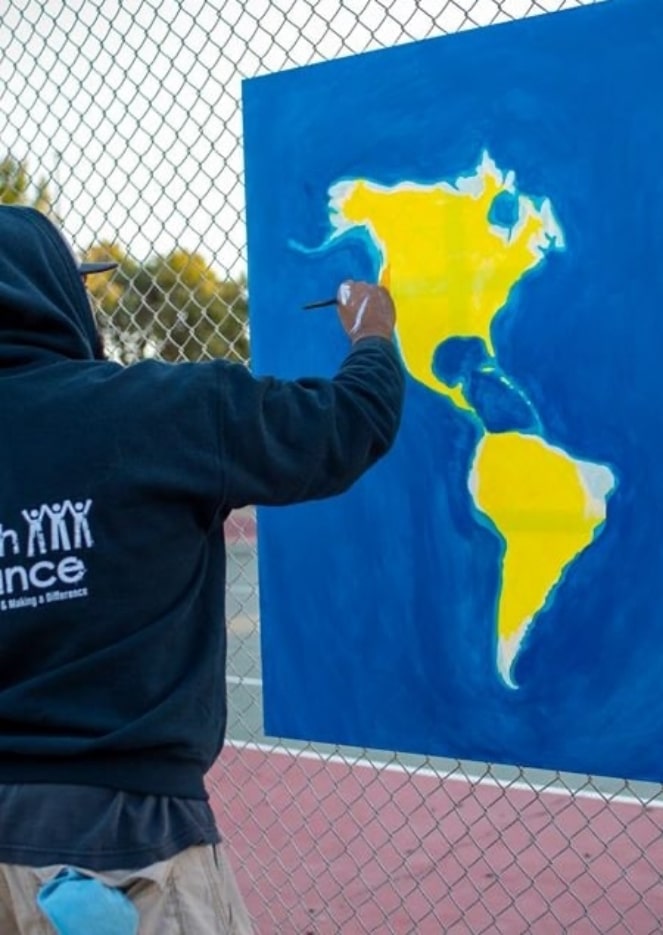 Artist painting continents North America and South America on canvas outdoors